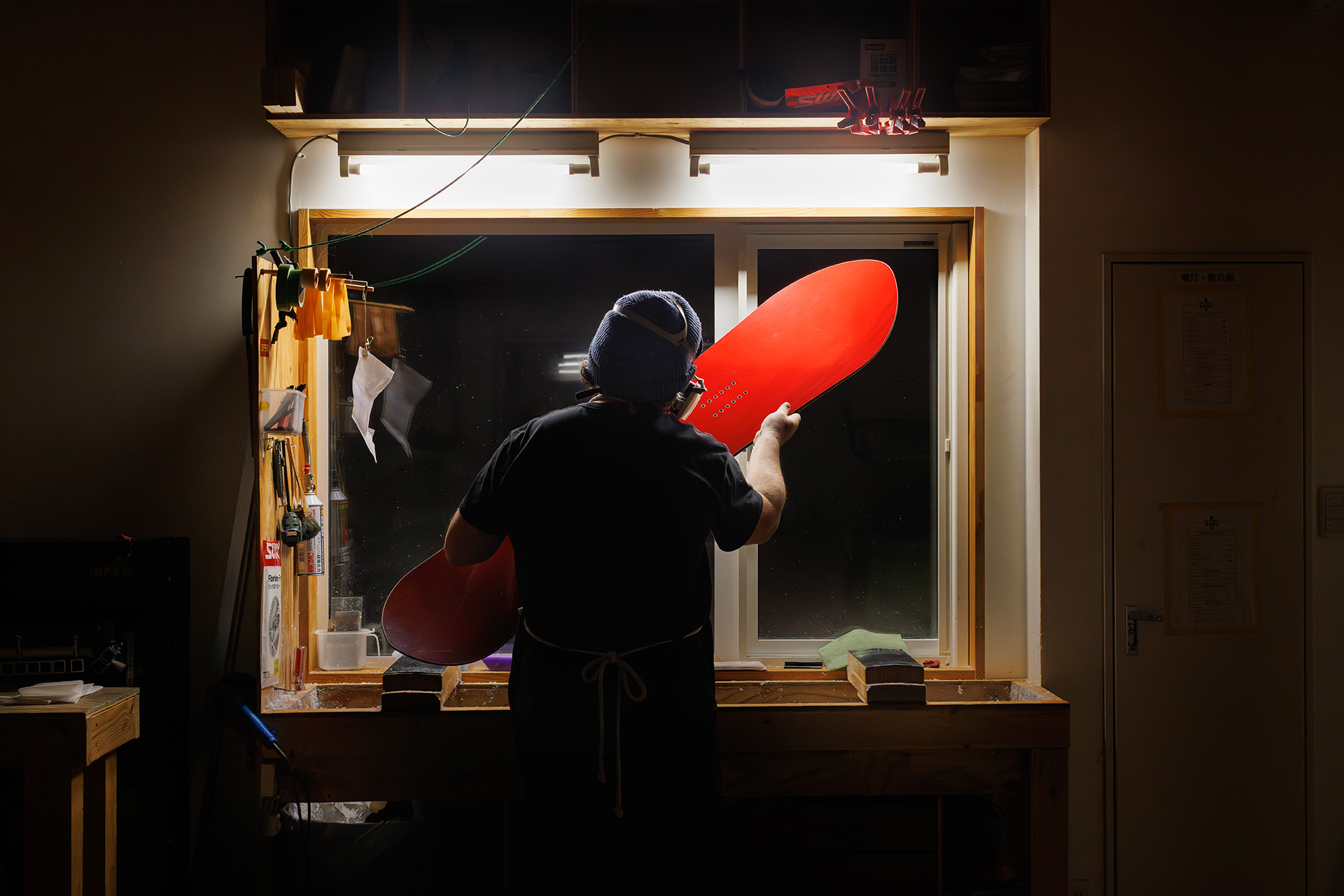 Josh Monin holding a red urushi board to the light in the Offshore workshop